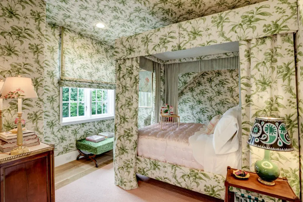 This secondary bedroom, designed by Lisa Fine, features upholstered walls, large closet, hardwood floors, built in bookcase, and ensuite bath.
