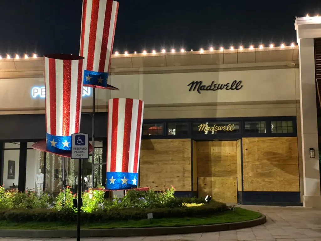 The boarded-up Madewell in Highland Village makes a poignant statement behind the early Fourth of July decorations.  (Photo by Shelby Hodge)