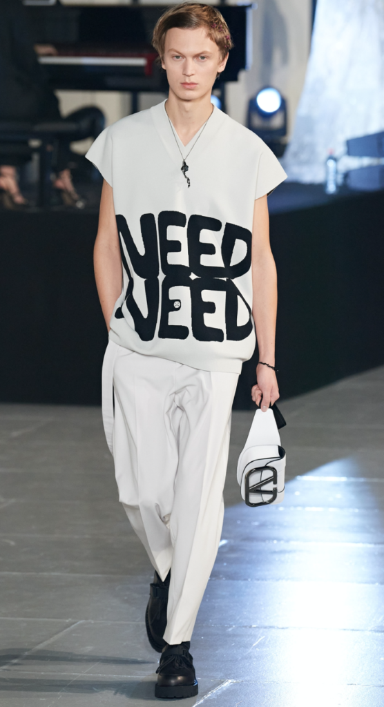 Might we suggest looking ever the man in the know via a tunic-like top emblazoned with "Need Need," paired with a gender fluid cross-body bag.
