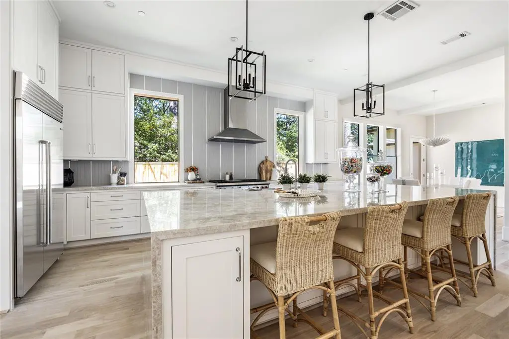 The kitchen features stainless steel SubZero and Wolf appliances with a gleaming quartzite island.