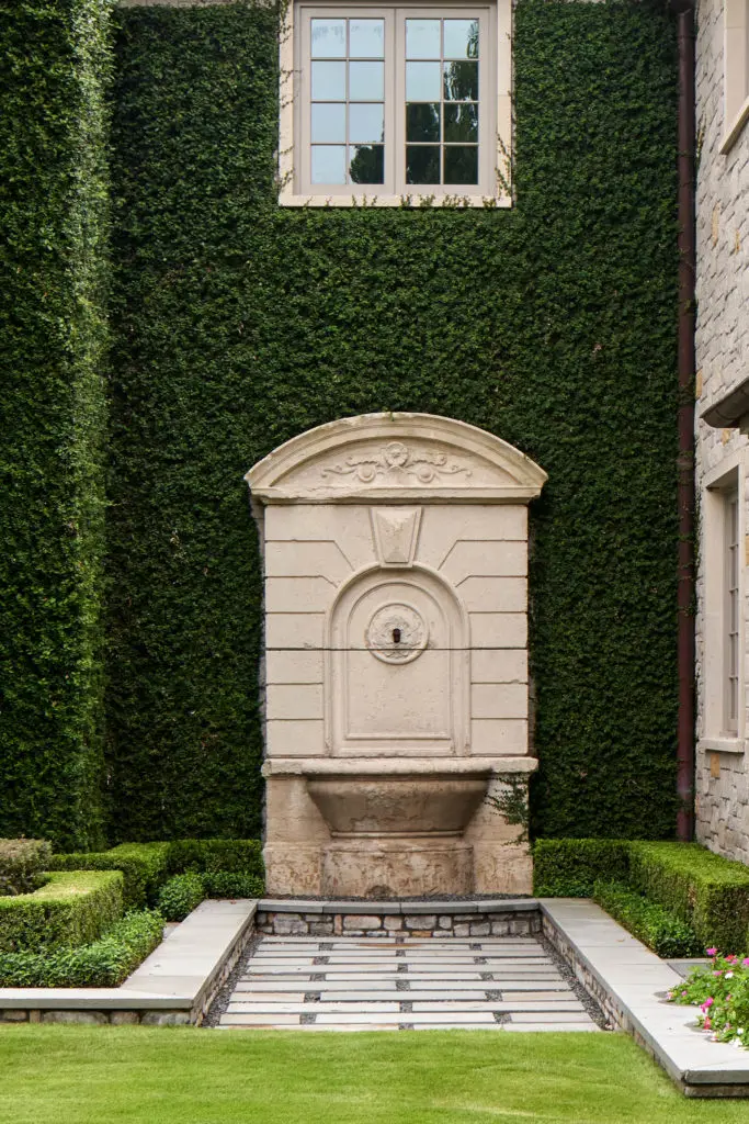 Ivy clad stone walls are accented with antique French fountains. (Photo by Nathan Schroder/Douglas Elliman)