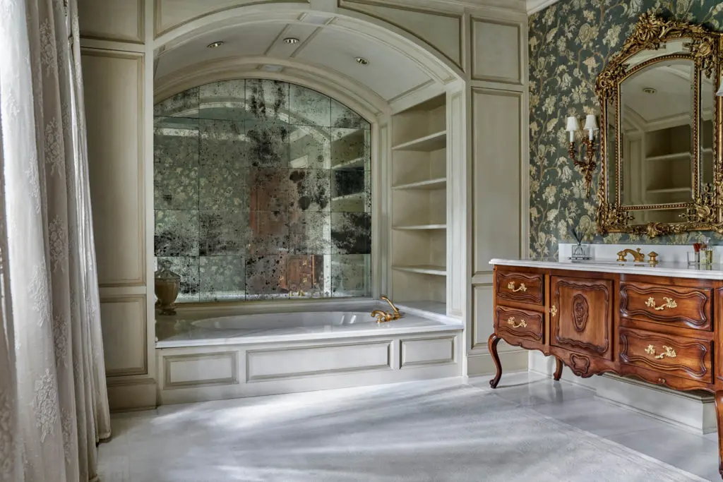 The lady's elaborate bath in the Carnarvon mansion features an  antique cabriolet-leg sink cabinet with sculpted marble deck, jetted tub surrounded by smoked mirrors, and an etched-glass and marble shower. (Photo by Nathan Schroder/Douglas Elliman)