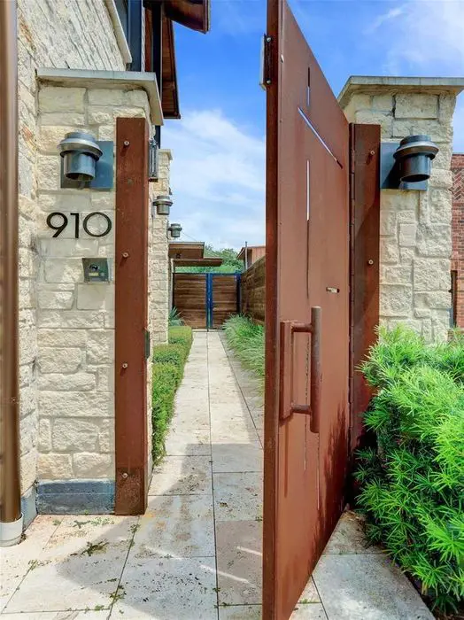 The iron gate opens to a path leading to the house entry.