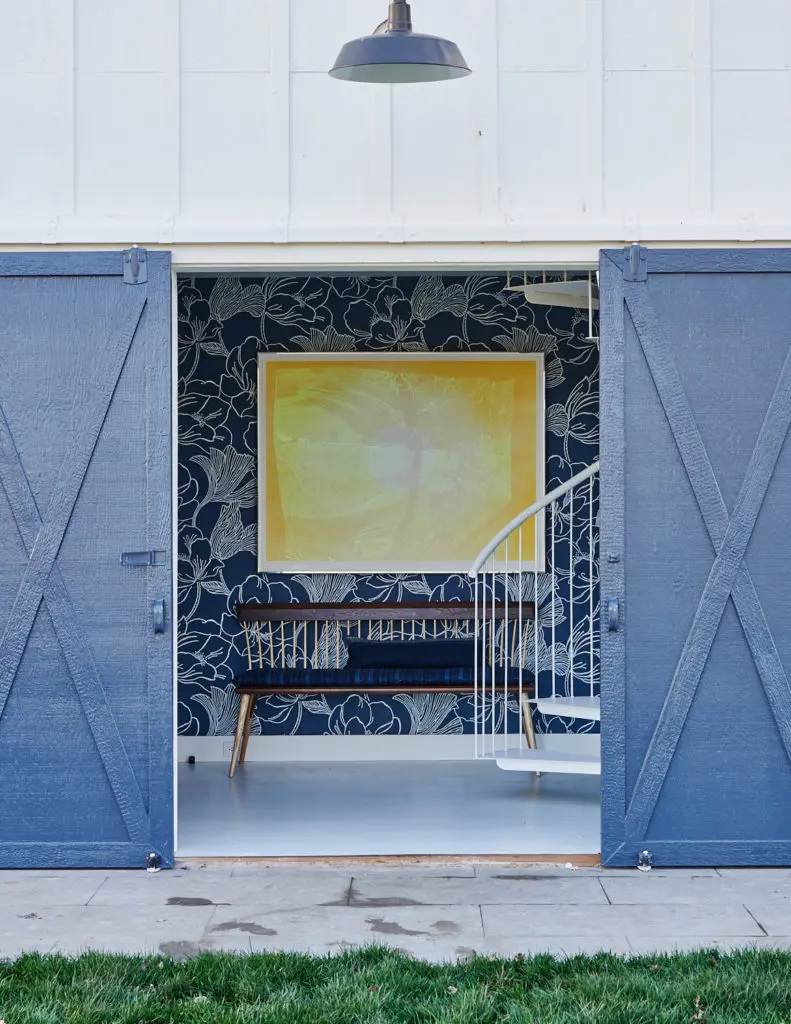 In a coastal home, a pair of barn doors are painted glossy cobalt. Wallpaper is Farrow & Ball. (Photo Amy Neunsinger)