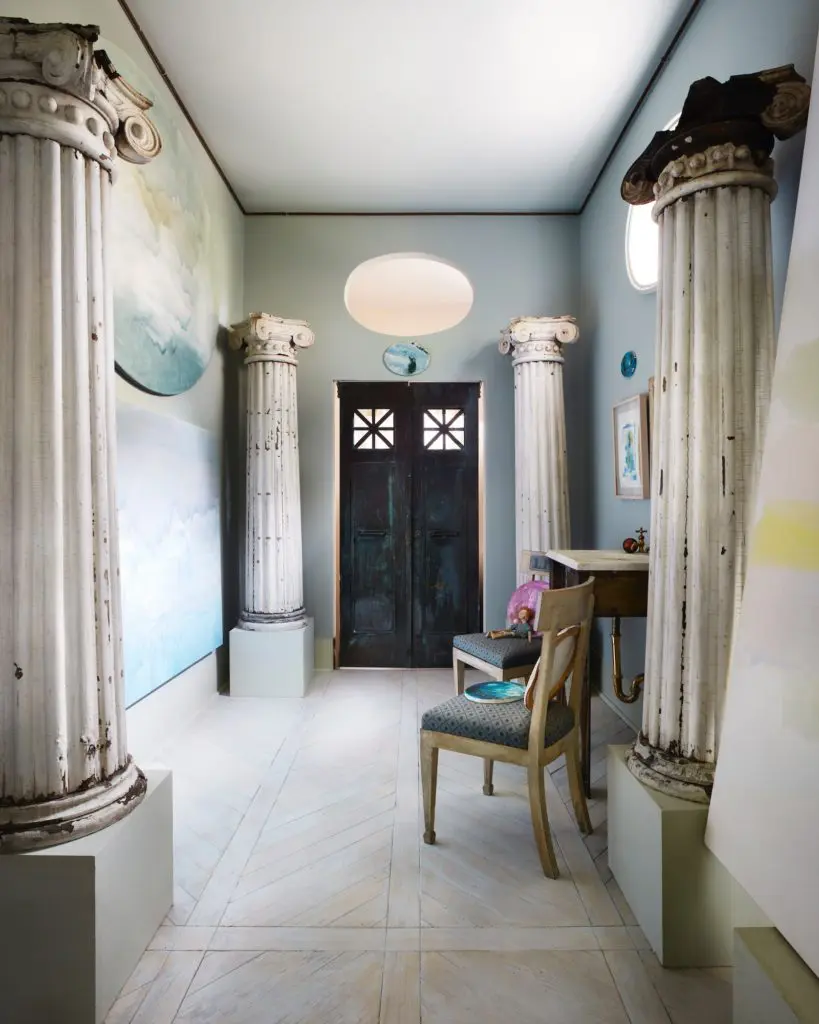 In a bath that looks more like an entrance hall, are antique bronze doors from a bank, salvaged columns, and a bronze basin. Paintings by Werner-Vaughn. (Photo by Lisa Petrole, Art Direction by Michelle Aviña)
