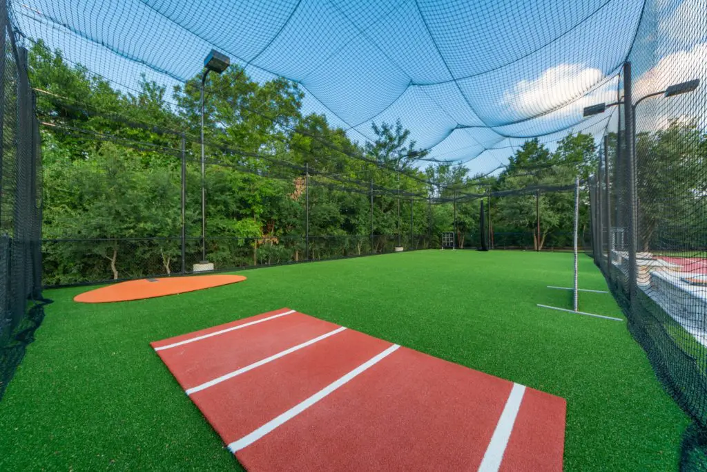 Batting and pitching cages are adjacent to the basketball court.