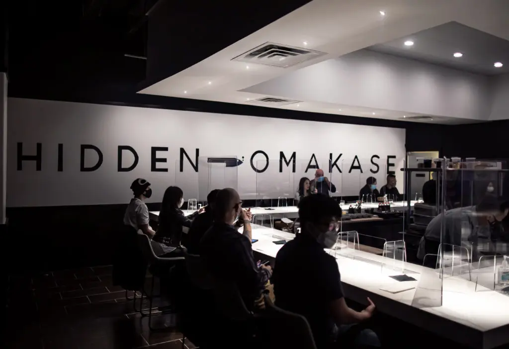 Diners sit socially distanced at Hidden Omakase's U-shaped counter top with Plexiglas dividers. (Photo by Katoe Productions)