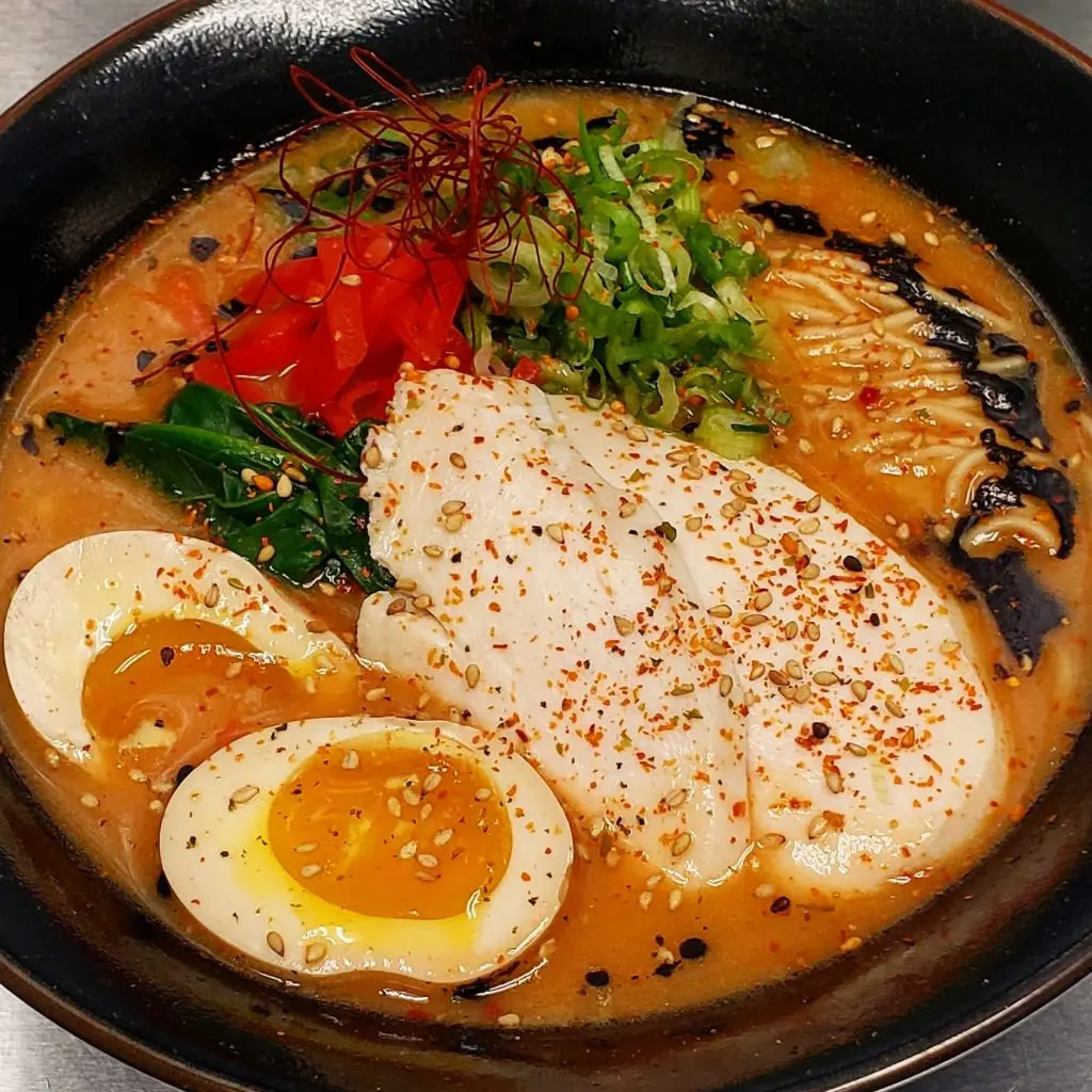 Kintaro Ramen's Karashi Paitan is a spicy creamy chicken broth topped with a mayu schmaltz, muneniku, six-minute egg, and pickled red ginger.