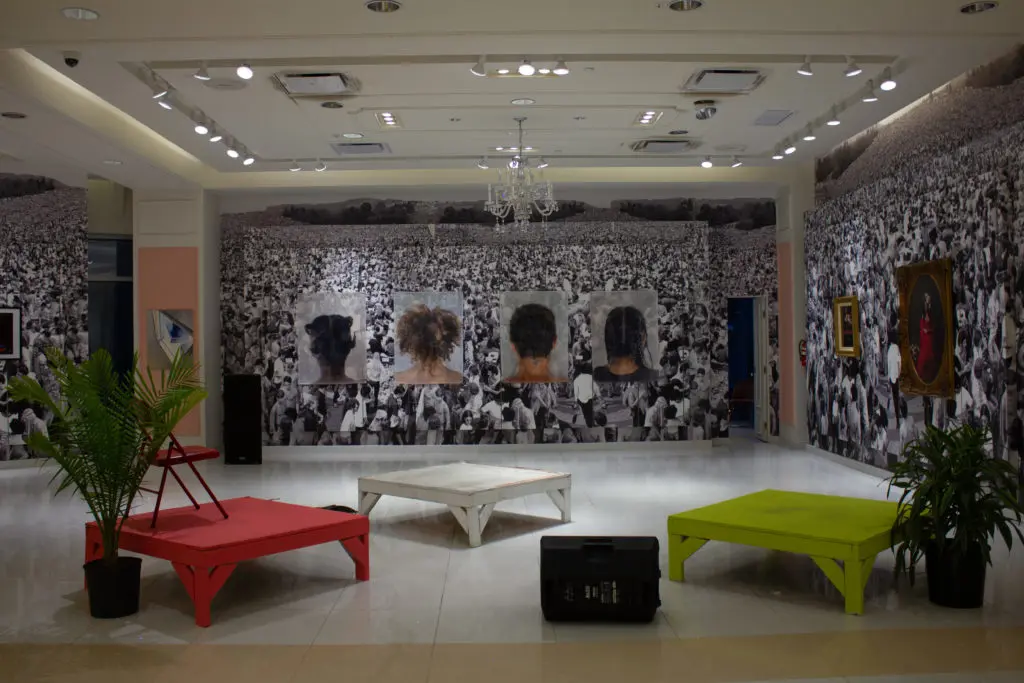 Empty stage before music arrives. Work by Rabéa Ballin  features the hairstyles worn during the pandemic and commands attention in the background. Rabéa Ballin's "Quarantine Portraits," 2020. (Photo by James Karroum)