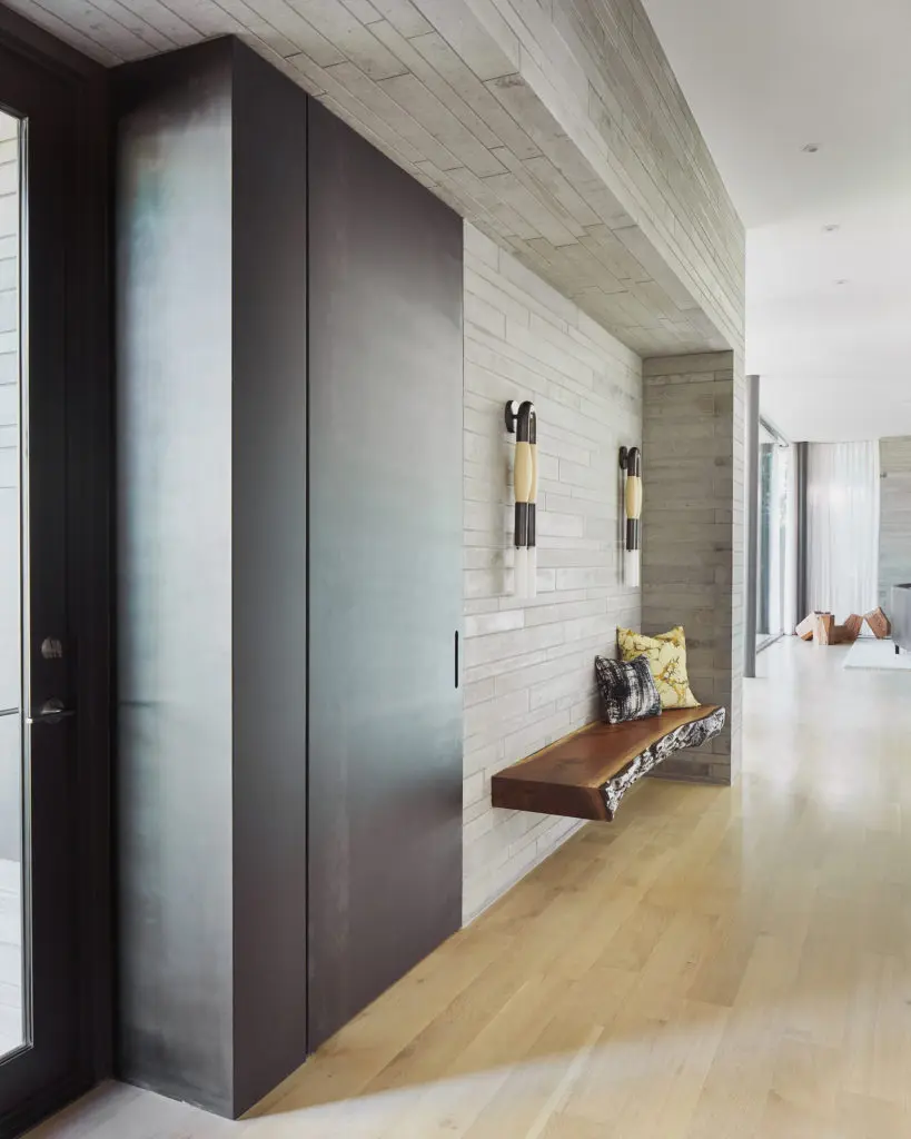 In the entry are a concealed blackened-steel coat closet, live-edge bench, and Apparatus bronze-and-horsehair sconces. (Photo by Stephen Karlisch)
