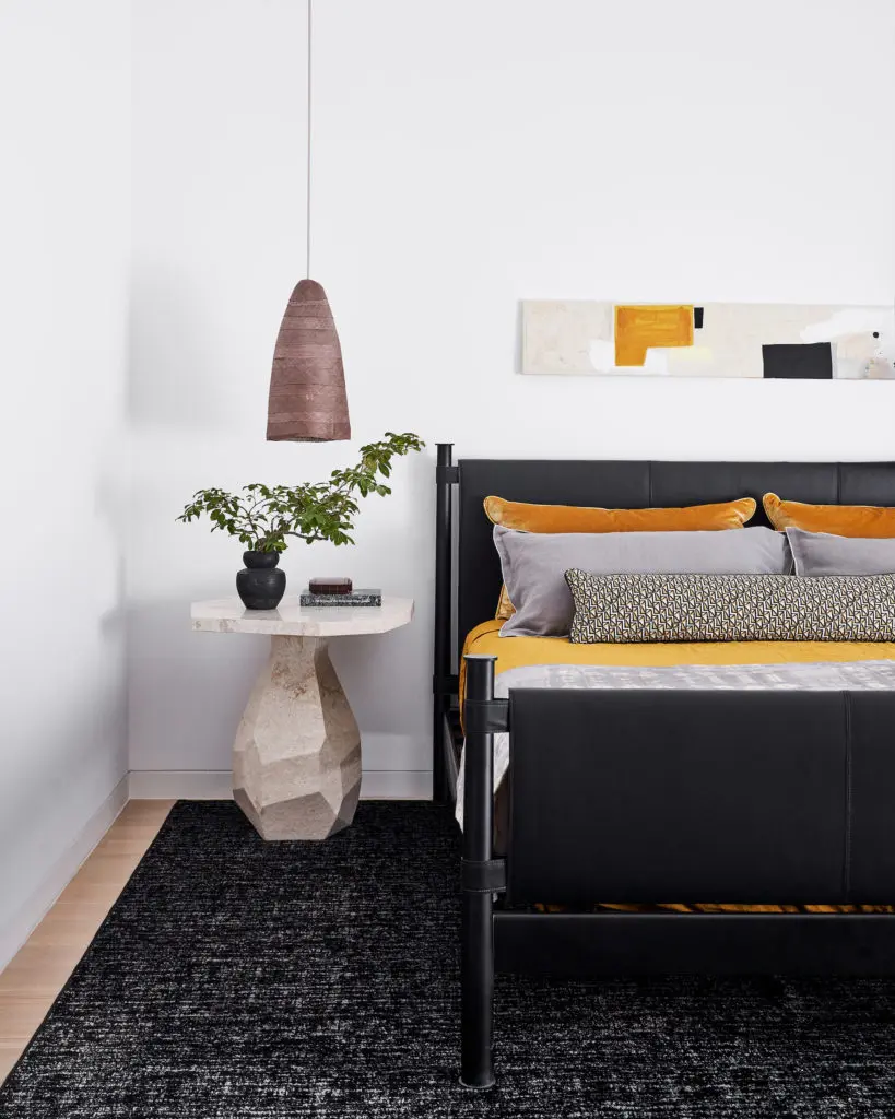 In a guest bedroom, Kara Mann for Baker
bed, straw pendant by Pinch Studio, Noir
marble table. Stark rug. Shams in Anthony George fabrics. Art by Amy Berlin Opsal. (Photo by Stephen Karlisch)
