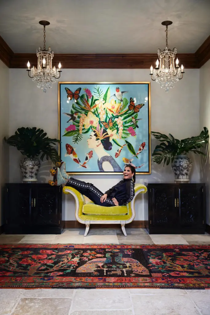 In the foyer, April Manson in her Moxie roller skates beneath a painting by New Orleans artist Ashley Longshore. Bench by Cuellar Custom Upholstery, in Pierre Frey velvet. Antique Turkish dowry rug. Vintage Henredon chests. Chandeliers original to the house. (Photo by Pär Bengtsson)