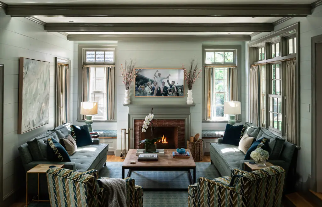 The family room steps down from the kitchen and breakfast area for a cozy feel. Custom chairs are upholstered in Lee Jofa cut velvet. Custom sofas in blue mohair, with turquoise velvet pillows. Built-in window seats, upholstered in Lee Jofa fabric, flank the TV above the fireplace. (Photo by Manny Rodriguez)