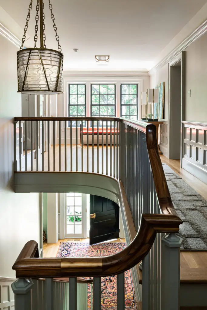 A back staircase banister in mahogany. The landing’s coffered wood wainscoting, white oak floors, and Ralph
Lauren for Visual Comfort light fixture add to the authentic feel. (Photo by Manny Rodriguez)