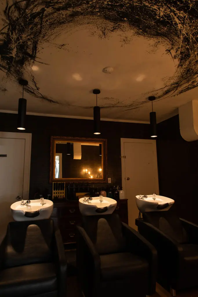 The wash room at Volume Social Club is purposely dark for client privacy. Artwork on the ceiling is a special Sergio Morales touch. (Photo by Leah Wilson)