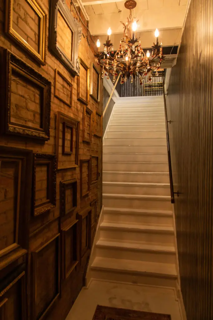 The art-lined stairway that leads to the second floor Volume Social Club salon. (Photo by Leah Wilson)