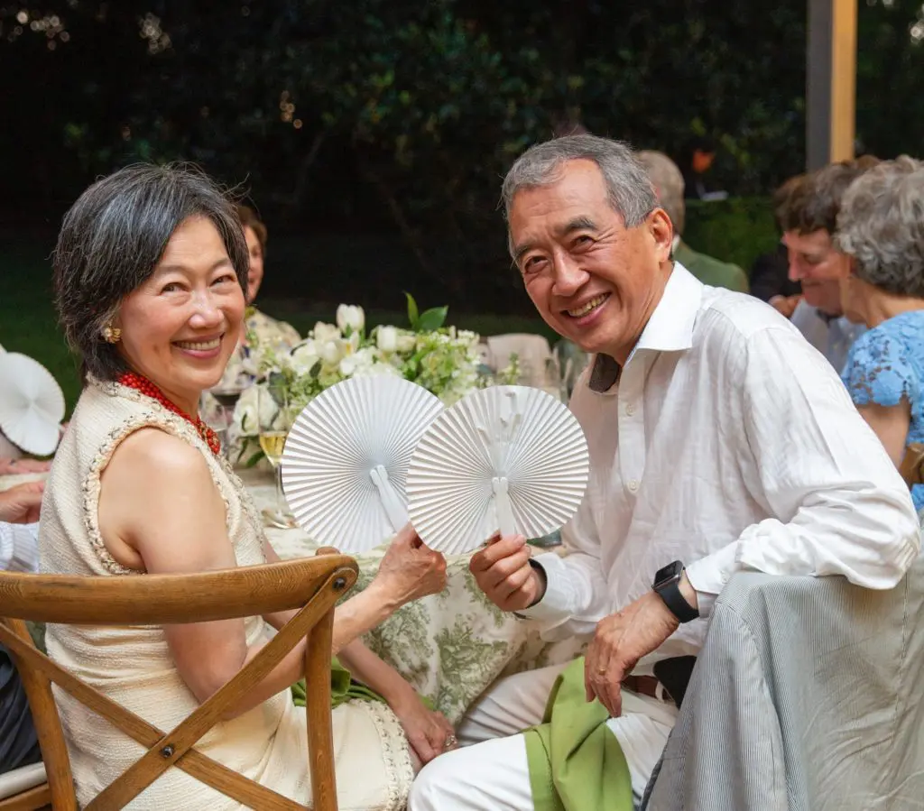 Anne & Albert Chao employ the paper fan handouts while dining al fresco at the annual Bayou Bend Garden Party. (Photo by Jenny Antill Clifton)