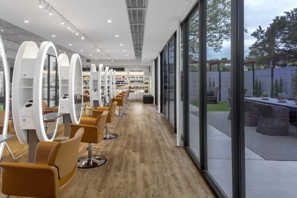 Large sliding glass doors at Therapy Hair Studio lead to a verdant patio.