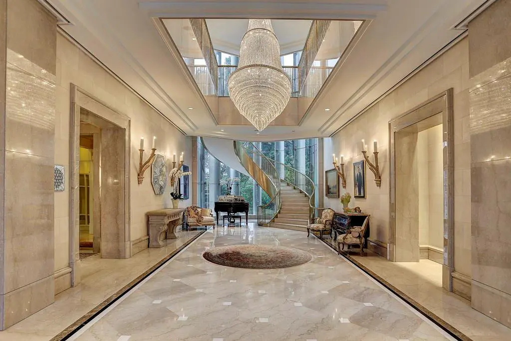 The dramatic floating staircase is the focal point of this spectacular foyer. The stunning marble treads and dual polished-brass balustrades float beautifully within an alcove of 35’ tall butted-glass windows,  (Photo by TK Images)