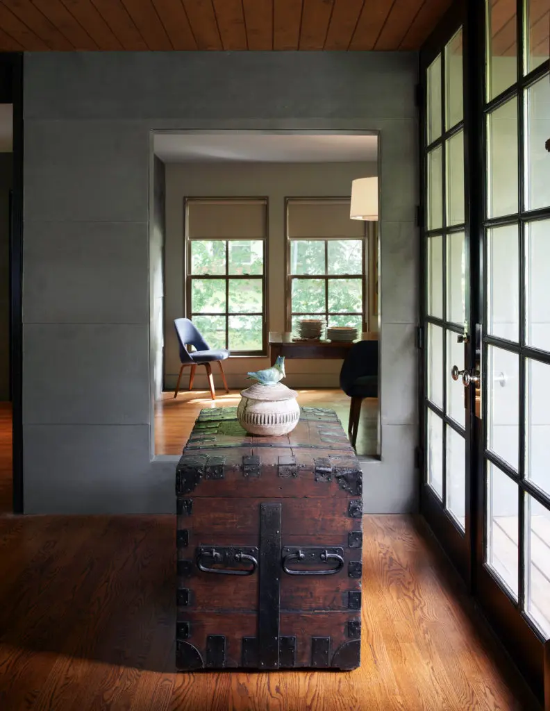 A zinc-paneled portal frames a view into the dining room. On an antique chest, light illuminates a clay vessel, topped with a Kingfisher bird, made by McCarty's Pottery in Merigold, Mississippi. (Photo by Pär Bengtsson)