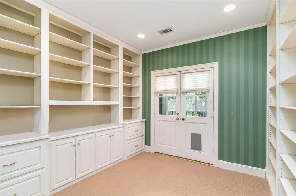 A roomy closet with a touch of elegant wallpaper. 