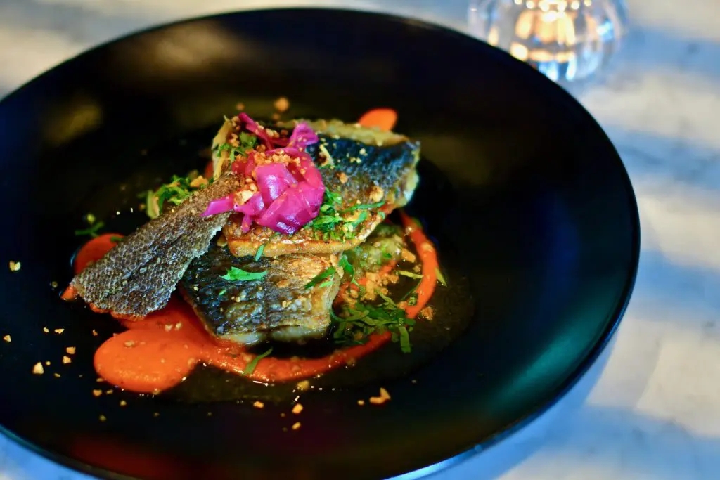  A grilled whole branzino fish is stuffed with cilantro and lime, served with a salsa verde and adobo sauce.  (Photo by Michael Anthony)