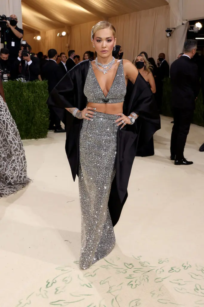 Rita Ora wears a Prada black duchesse crop top and pencil skirt entirely covered with faceted crystals paired with a black satin cape. (Photo by John Shearer/WireImage)