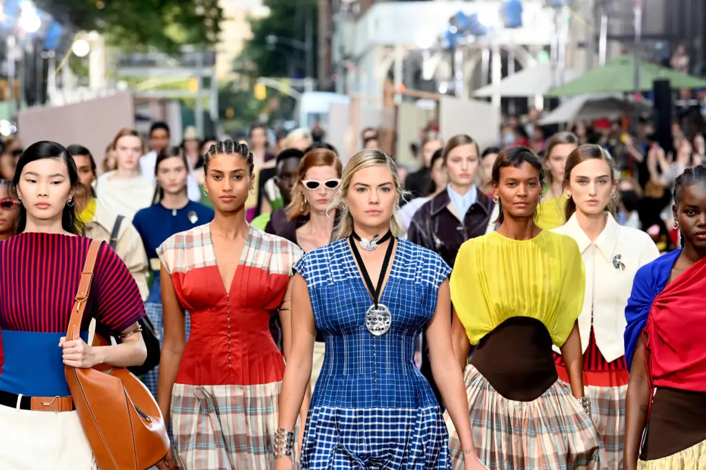 Kate Upton, center, wears a Tory Burch picnic plaid silk dupioni dress
with grid-pattern bodice, embossed Lampshade bag, and link lace-up sandal. (Photo by Slaven Vlasic/Getty Images for Tory Burch)