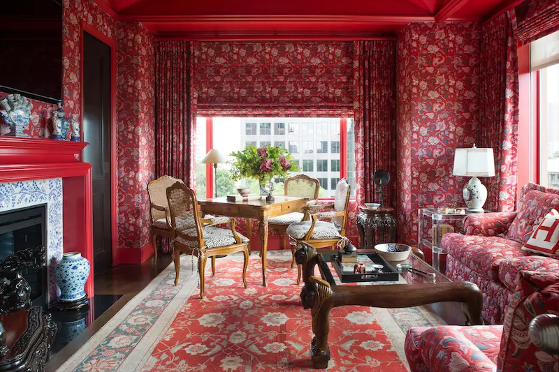 In the library, walls, windows, and upholstered sofa and chair are covered in red Persian chintz by Colefax and Fowler, the same fabric used by Billy Baldwin to envelop Diana Vreeland's "Garden in Hell" Park Avenue living room. (Photo: Emily Minton Redfield)