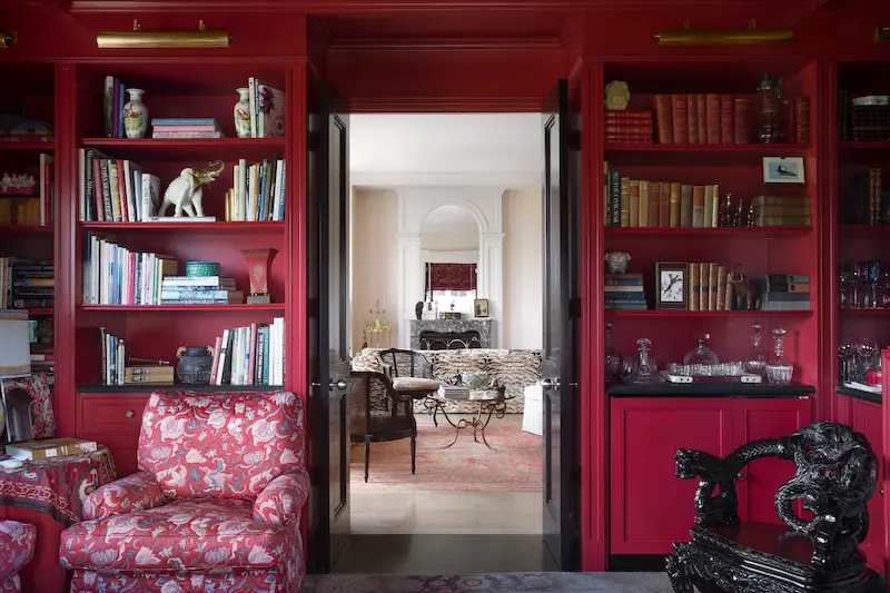 Walls and ceiling are lacquered red. Shelves hold objects picked up during the homeowner's travels. The ornately carved chair is an antique from Asia. (Photo: Emily Minton Redfield)