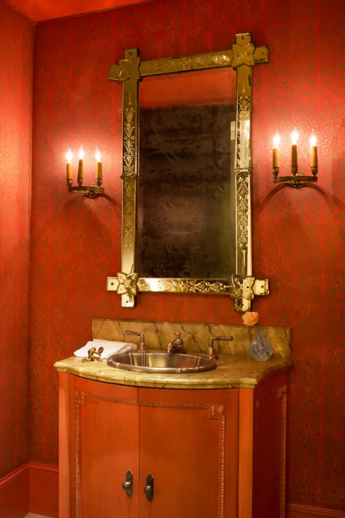 Walls and vanity of the powder bath are covered in vintage Fortuny fabric that belonged to the homeowner. Antique Venetian glass mirror. (Photo: Emily Minton Redfield)