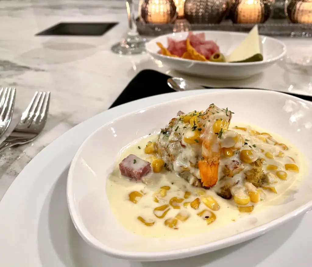 Grilled shrimp topped a lump crab cake in a corn maque choux cream sauce, with crispy pancetta. Photo by Courtney Dabney.