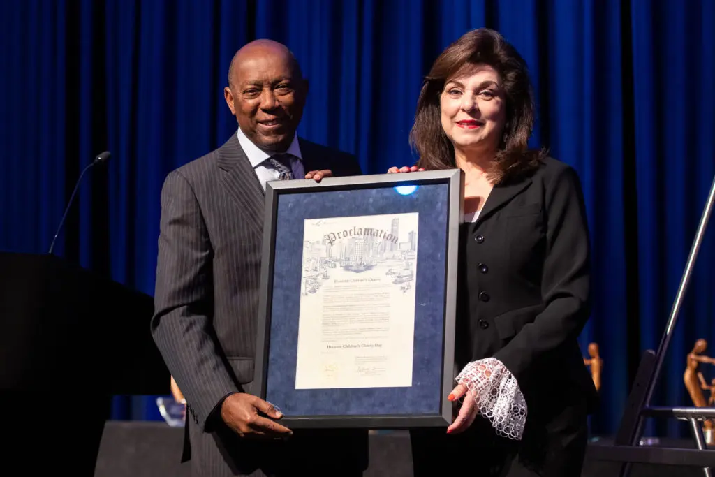 Mayor Sylvester Turner with Laura Ward declares it Houston Children's Charity Day in Houston on the occasion of the nonprofit's 25th anniversary luncheon, 2021 (Photo by Michelle Watson, catchlightgroup.com)