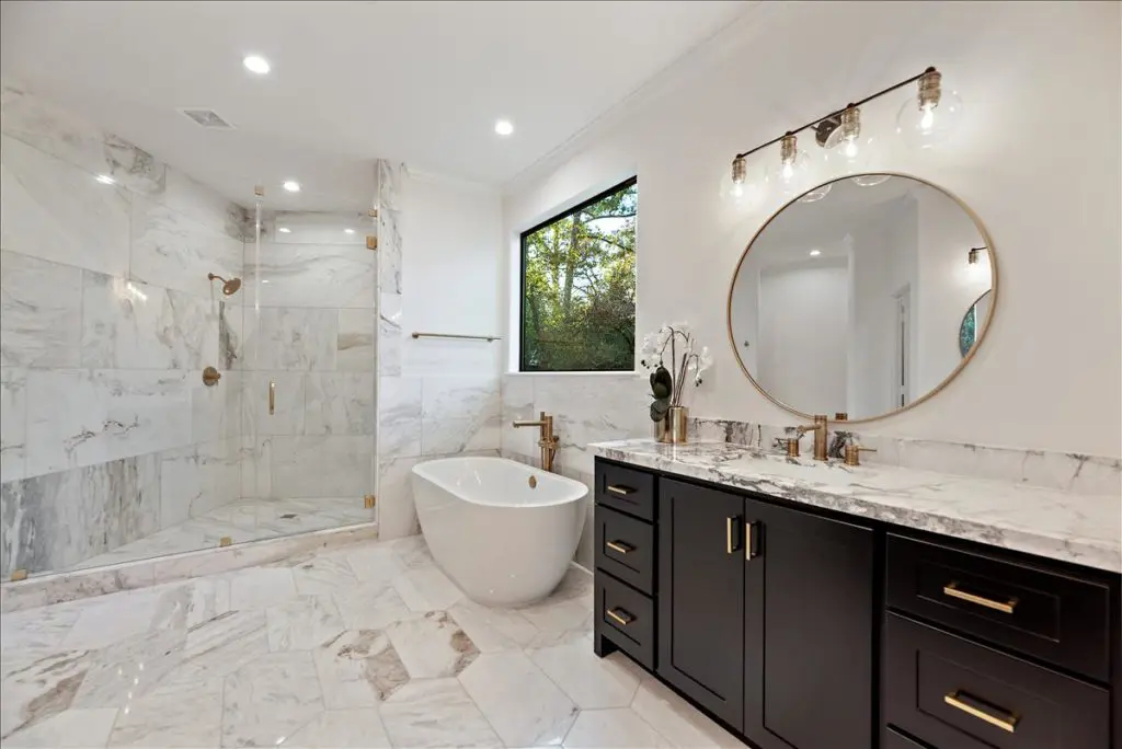 A primary suite complete with a spacious spa-like bath and dual dressing rooms is located downstairs in one wing of the home
