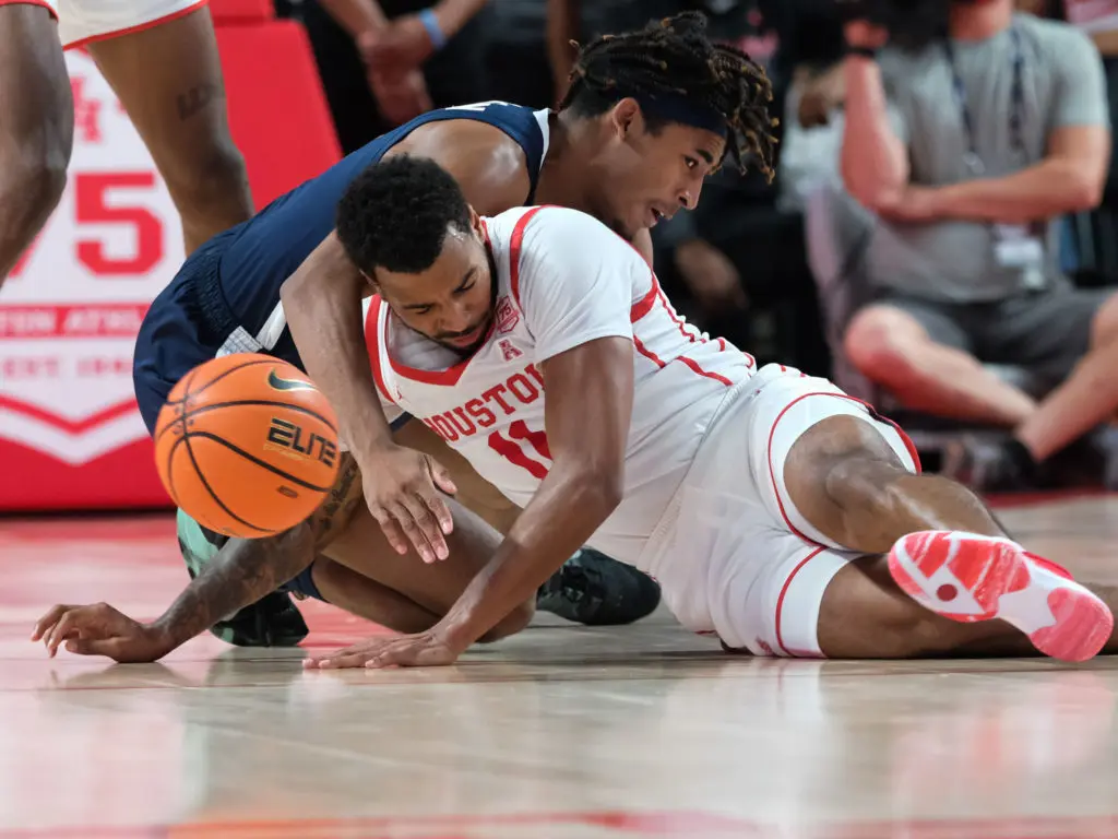 Kyler Edwards is not afraid to get on the floor and scrap for the basketball. Taze Moore skies high to challenge the shooter. (Photo by F. Carter Smith)
