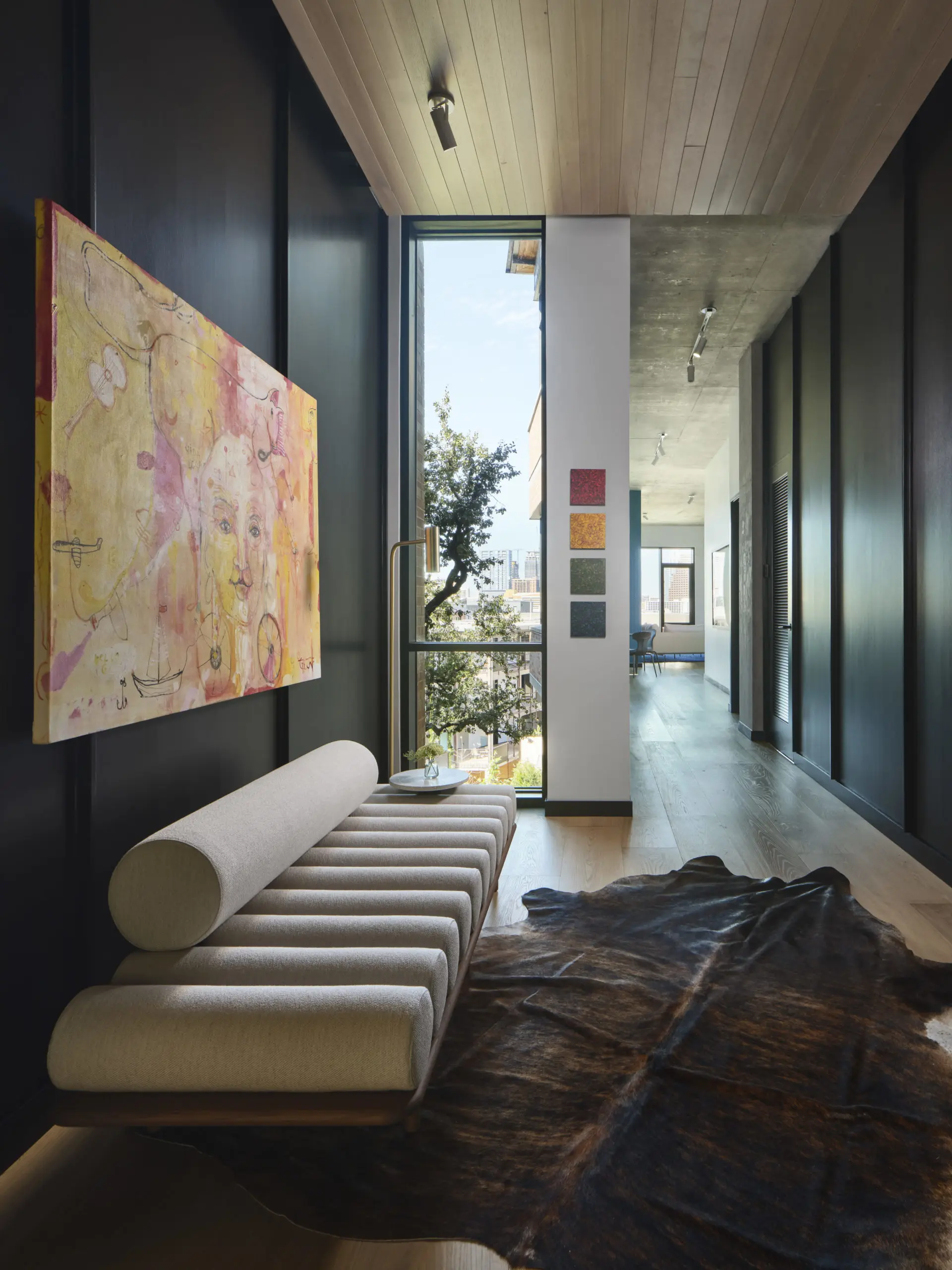 A sculptural Tacchini daybed paired with authentic cowhide for traditional Texas flair in this  entry foyer.  International artwork by Yvan Genest ”From Mexico to India” and local artist John David Robbins “Drips" mini series. (Photography by Andrea Calo)