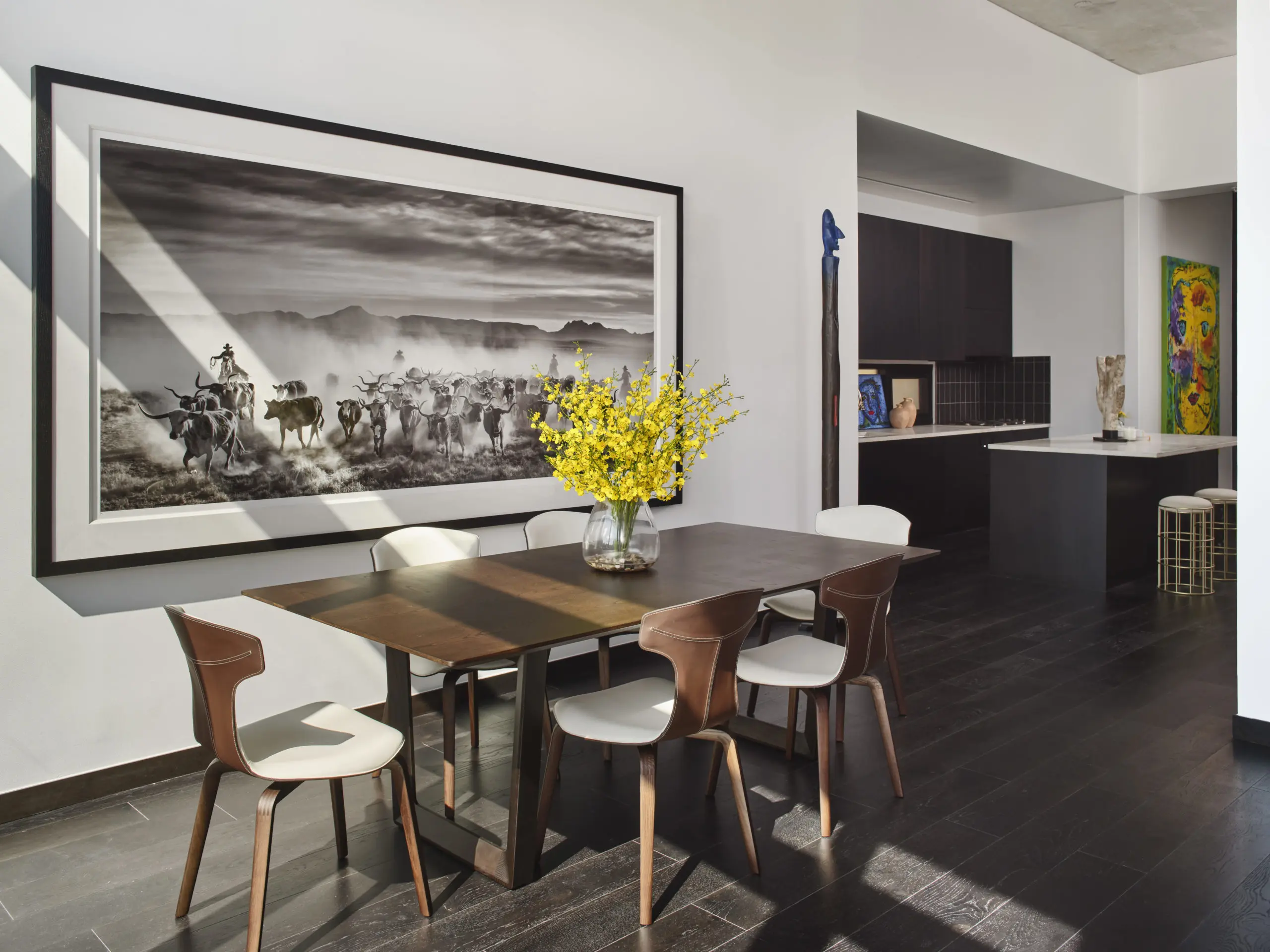 David Yarrow’s largescale “The Thundering Herd” artwork paired perfectly with a sleek Poltrona Frau dining table and
brown leather dining chairs for the light-filled dining room with floor to ceiling windows. For pops of color, Ana Tatya Neri “Punked” artwork in kitchen. (Photography by Andrea Calo)