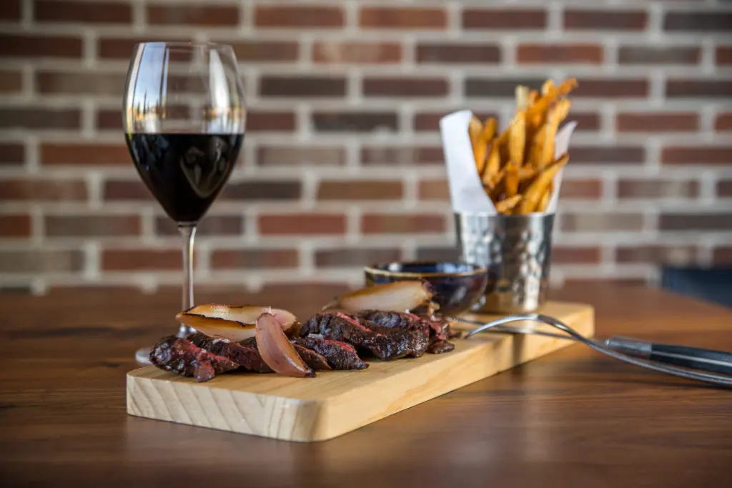 The steak frites ($42) are made with hanger steak topped with charred shallot slices with duck-fat fried potatoes and a smoked onion bearnaise. (Photo by Photos Care of Back Table Kitchen & Bar)
