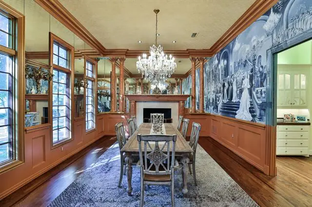 A fireplace, wooden columns and lavish chandelier overhead in the dining room.