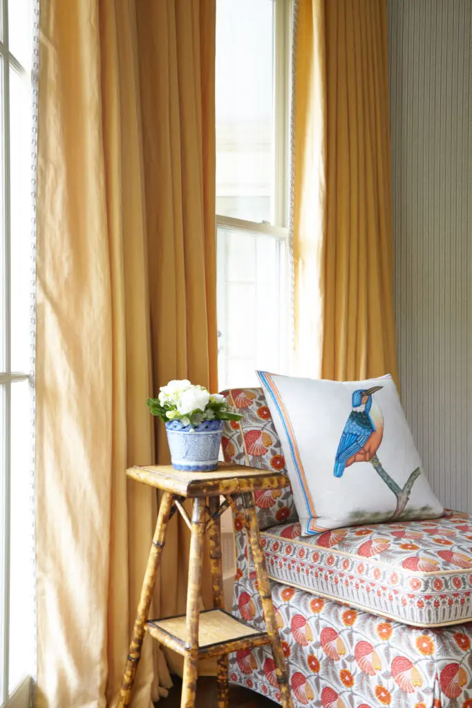 A corner with a bamboo table in a tortoiseshell pattern. A charming bird pillow echoes the room’s avian theme. (Photo by Tria Giovan)