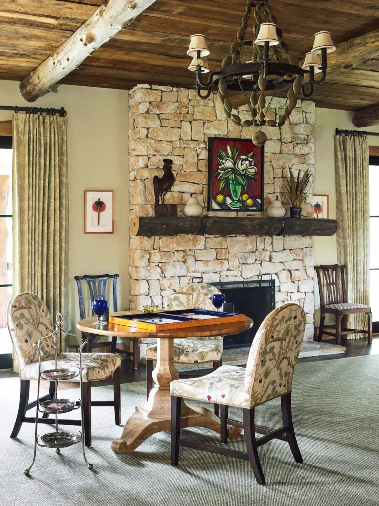 Repurposed oak ceilings, beams, and a large stone fireplace give the main living area a rustic, masculine feel. Artwork over the fireplace is by David Bates from Talley Dunn Gallery. (Photo by Tria Giovan)