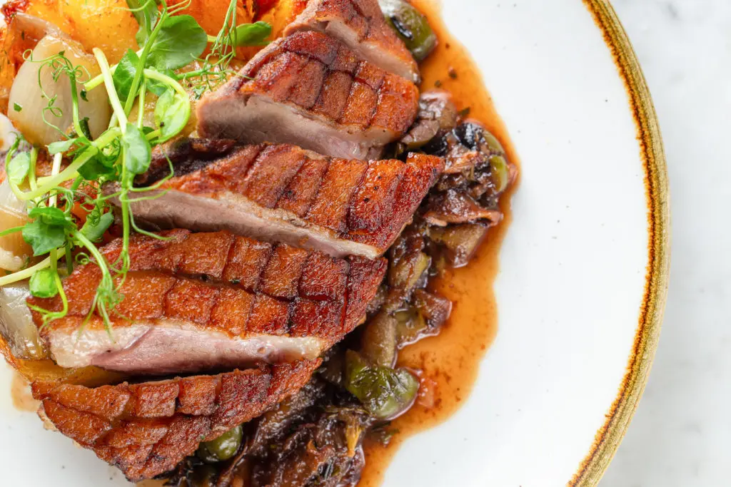 Roasted duck breast with grapes and olives roasted in port, duck fat potato, shallot confit is new on the Brasserie 19 menu. (Photo by Andrew Hemmingway)