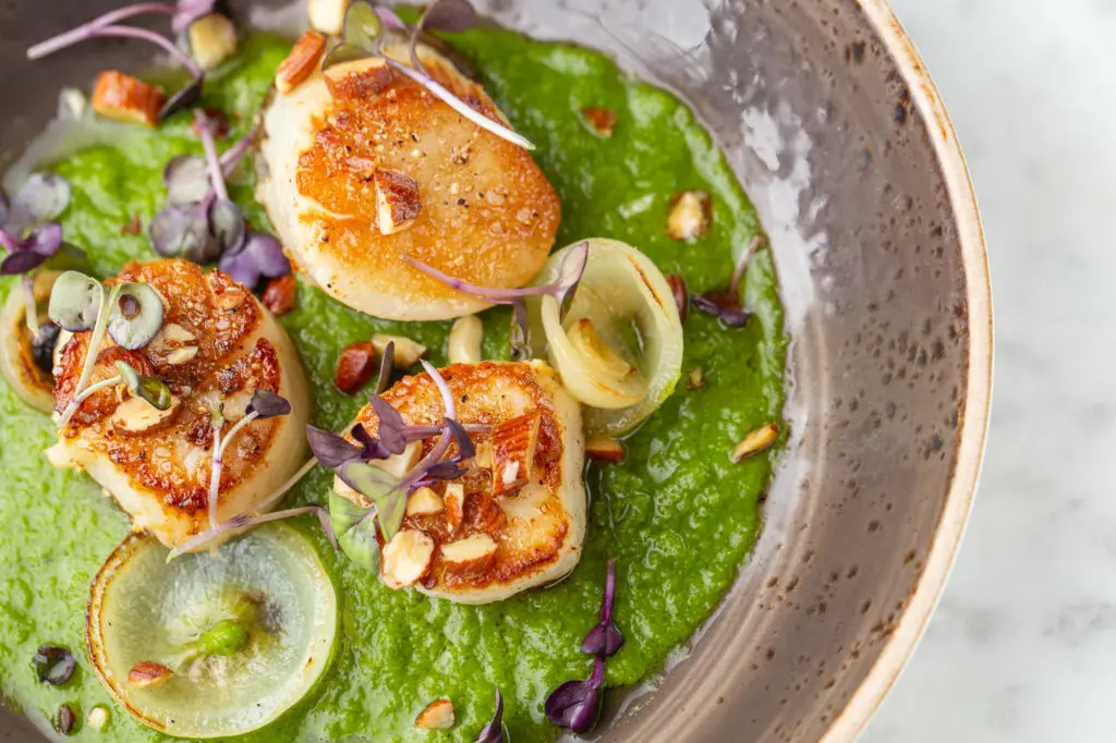 Seared scallops served with green gazpacho, charred cippolini onion, smoked almond is new to the Brasserie 19 menu. (Photo by Andrew Hemmingway)