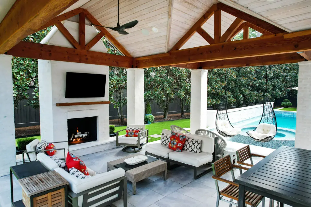 The covered patio at 802 E. Friar Tuck Lane welcomes seamless indoor-outdoor living surrounded by a fireplace, summer kitchen, pool, and sports court. (Photo by TK Images)