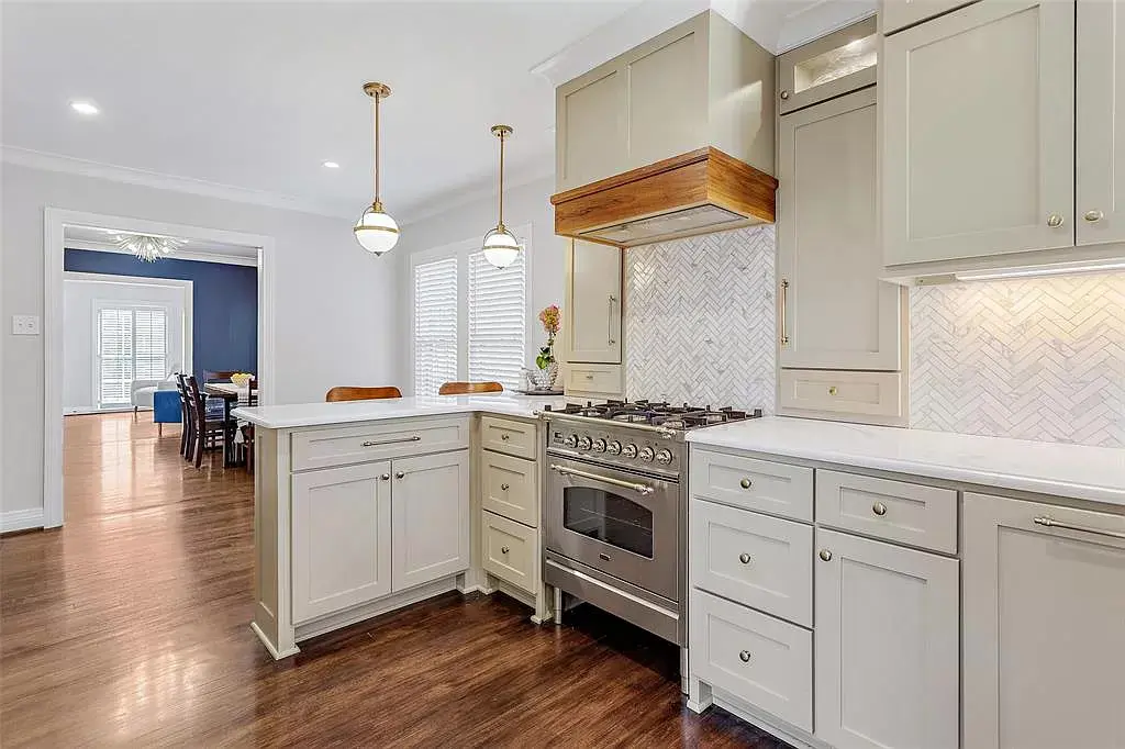 An updated chef's kitchen features high-end appliances and fresh green cabinetry. 