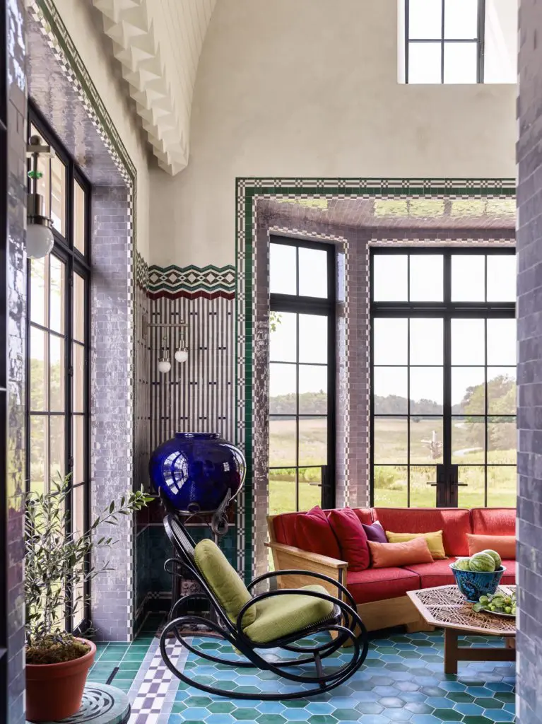 The walls of the screened porch are clad in green, burgundy, gray, and purple Moroccan zellige tiles in patterns inspired by the work of Koloman Moser and Joseph Urban. 