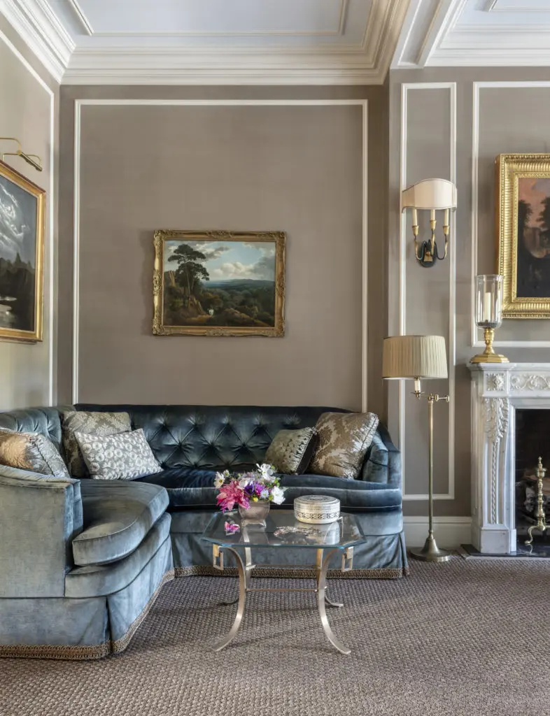 French art deco sconces with verdigris-finished frames and gilt Egyptian-influenced details, and Louis XVI–style photophores on the mantel add to the layering of history in the room.