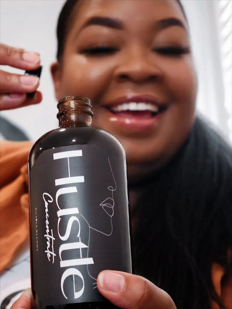 Patrice Angwenyi opens a bottle of Hustle Concentrate housemade cold brew from HustleBlendz.