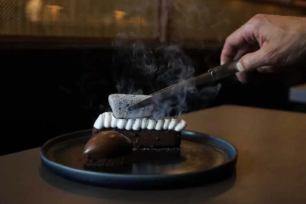 The S'Mores Dessert is a fun treat at Uchiko where the marshmallow-topped log of rich dark chocolate is seared tableside with a piece of red-hot compressed binchotan wood. (Courtesy of Hai Hospitality) 