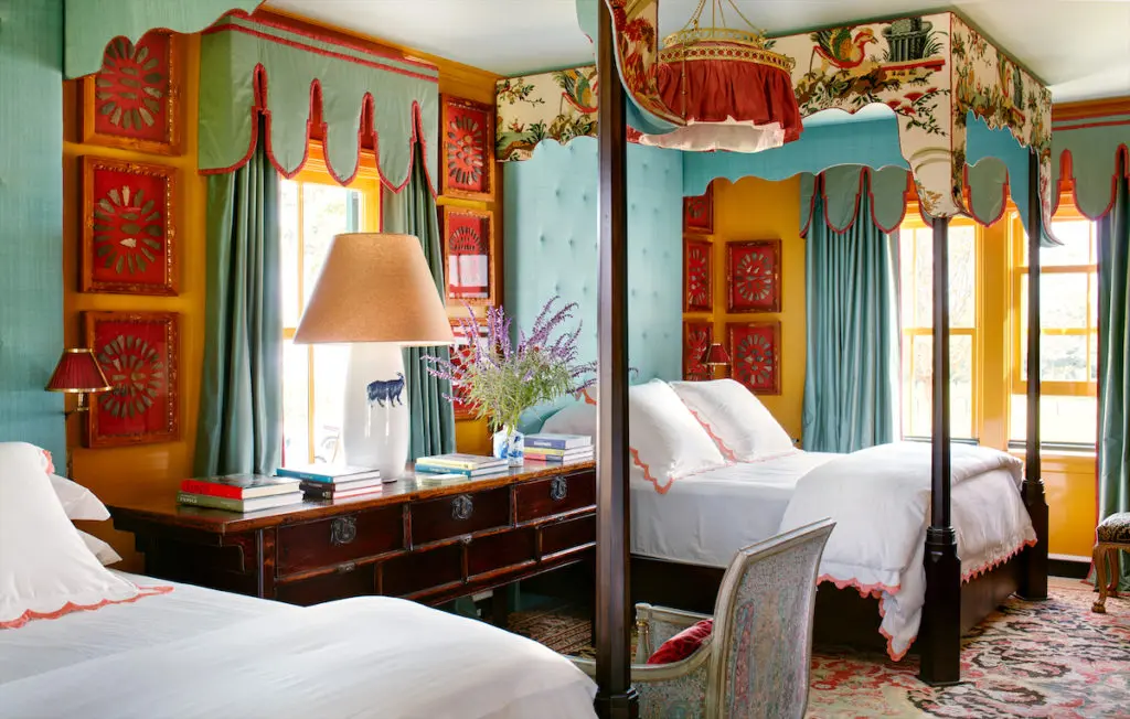 A guest bedroom on the first floor with canopied twin beds in Brunschwig & Fils fabric. Linens by Biscuit Home. A collection of framed arrowheads inherited from Pete’s parents hang salon-style on yellow-lacquered walls. (Photo by Trevor Tondro and Otto )